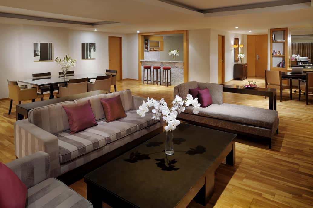 living room with grey couches brown coffee table and stools in the background