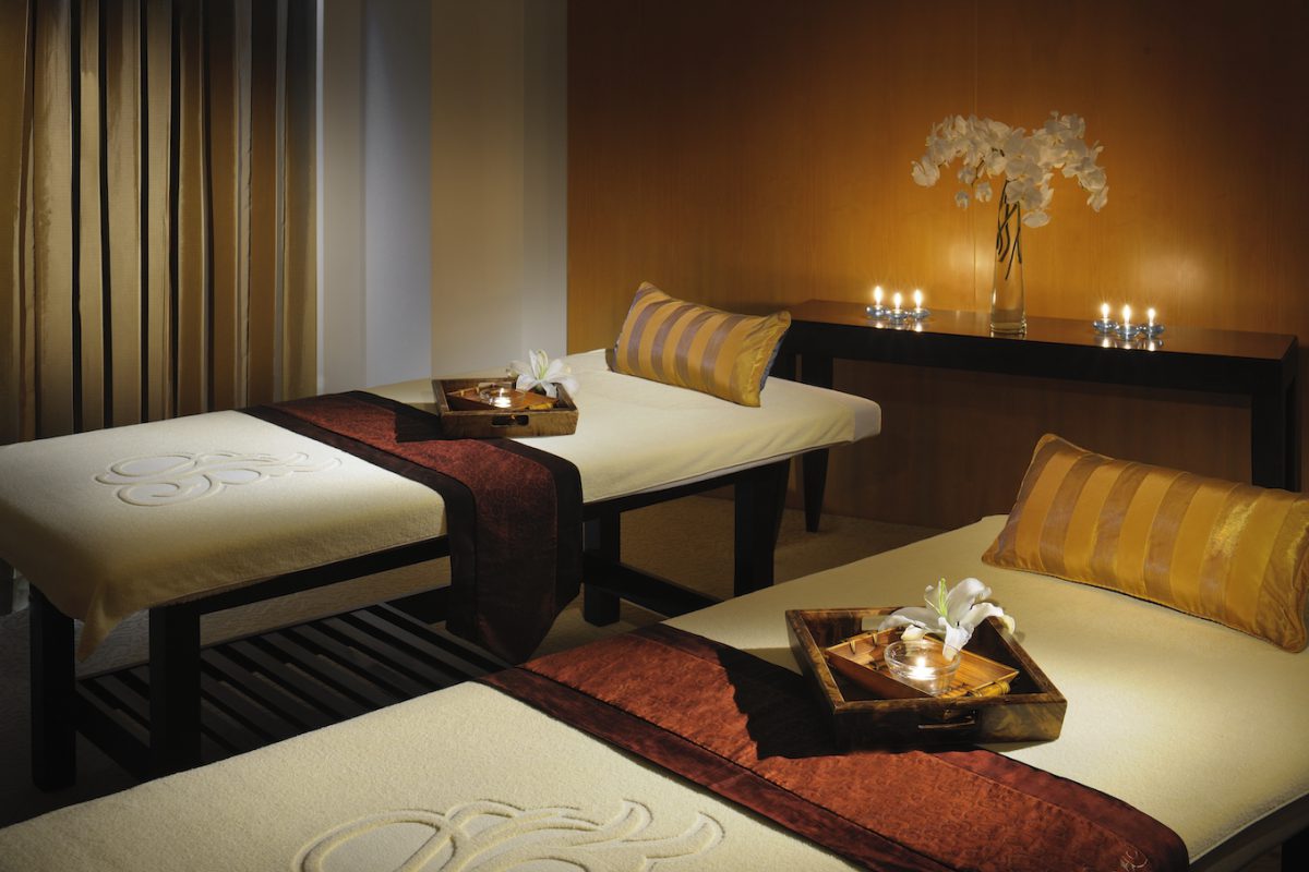 2 spa beds trays with oils and flowers table with vase and candles